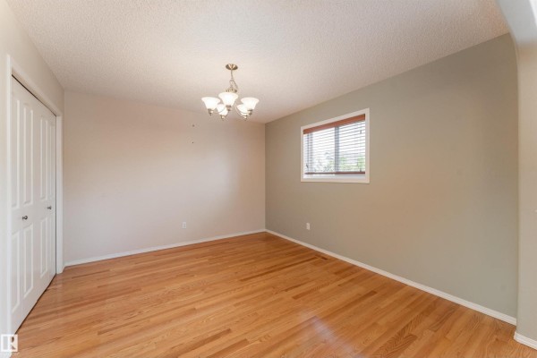 Dining room with hardwood floors, light gray walls, and a window. - 812 Barnes Link Sw, Edmonton