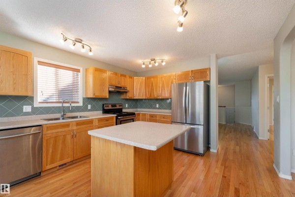Interior view of a spacious kitchen with light wood cabinets and stainless steel appliances. - 812 Barnes Link Sw, Edmonton