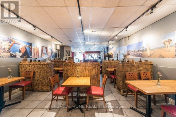 Restaurant seating area with wooden tables, red chairs, and decorative bamboo dividers. - 812 Bloor Street W, Toronto