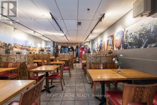 View of the restaurant interior showing multiple tables, chairs, and extensive wall murals. - 812 Bloor Street W, Toronto