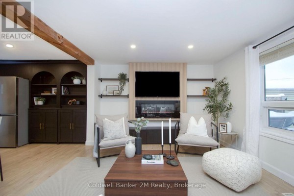 Another angle of the living room showing built-in shelves, a fireplace, and comfortable seating. - 812 Burnham Street, Cobourg