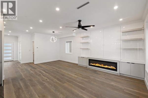 Open concept living space with white walls, hardwood floors, built-in cabinetry, and a modern fireplace. - 812 Montroyal Boulevard, North Vancouver