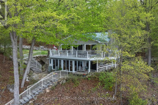 Living room with large sliding glass doors and stone patio view of a lake. - 8126 Perth Road, South Frontenac