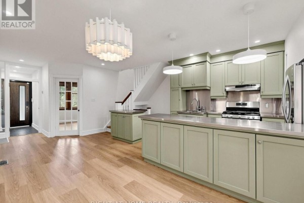 Kitchen island with sage green cabinets and stainless steel appliances in an open-concept space. - 813 Carlaw Avenue, Toronto