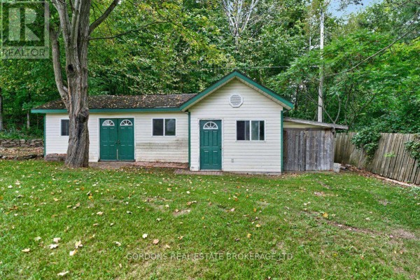 Small white building with two green double doors and two green single doors, surrounded by grass. - 813 Pierce's Lane, Leeds And The Thousand Islands