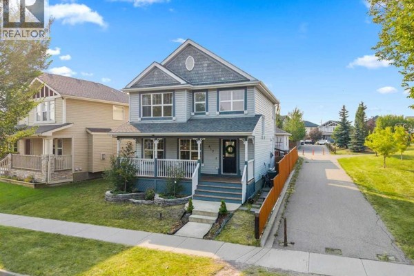 Aerial view of a grey two-story house with a white railing front porch and adjacent driveway. - 813 Prestwick Circle Se, Calgary