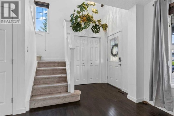 Interior entryway with carpeted stairs, dark wood floor, and double white doors. - 813 Prestwick Circle Se, Calgary
