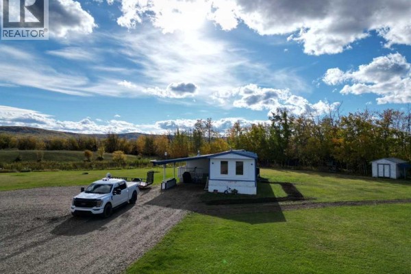 Aerial view of the white mobile home with a blue-roofed carport and driveway. - 8135 Township Road 782, Rural Saddle Hills County