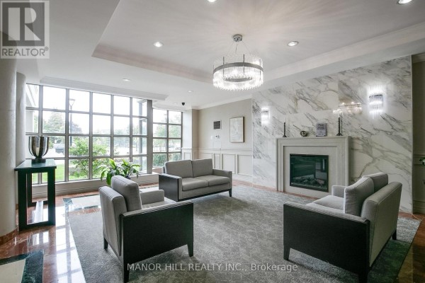 Lobby with fireplace, grey sofas, chairs, and marble accent wall. - 814 - 11 Townsgate Drive, Vaughan