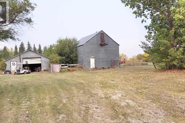 A corrugated metal outbuilding with an open garage door, a golf cart, and farm equipment outside. - 81404 Rr223, Rural Northern Sunrise County