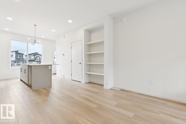 View of the kitchen island and living room, with a built-in bookshelf and white walls. - 8148 228 St Nw, Edmonton