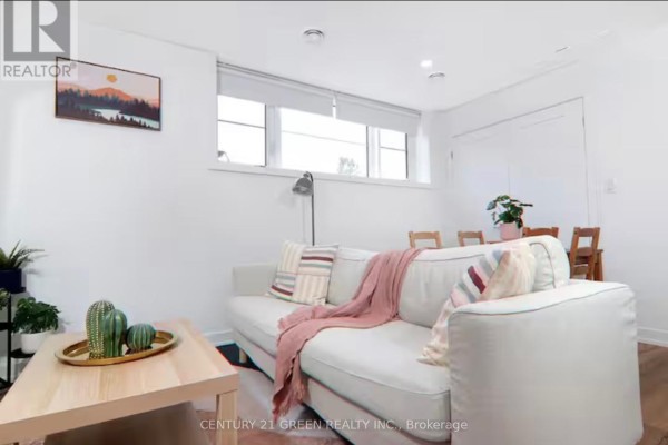 Living room area with white couch, pink throw blanket, wooden coffee table, and wall art. - 815 - 4263 Fourth Avenue, Niagara Falls