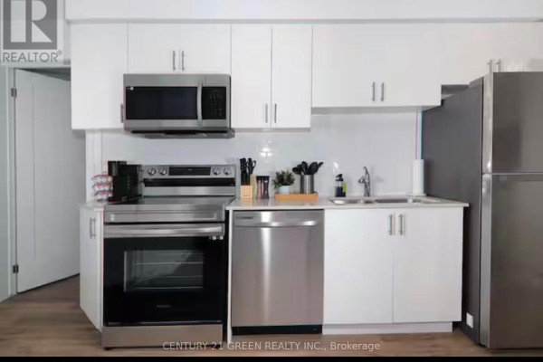 Open-concept living and kitchen area with dining table, white cabinets, stainless steel appliances, and hardwood floors. - 815 - 4263 Fourth Avenue, Niagara Falls