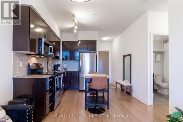 Open concept kitchen and living area with dark wood cabinets and stainless steel appliances. - 815 - 7167 Yonge Street, Markham