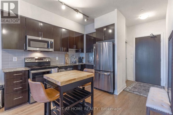 Kitchen area with dark cabinets, granite countertops, and stainless steel appliances. - 815 - 7167 Yonge Street, Markham