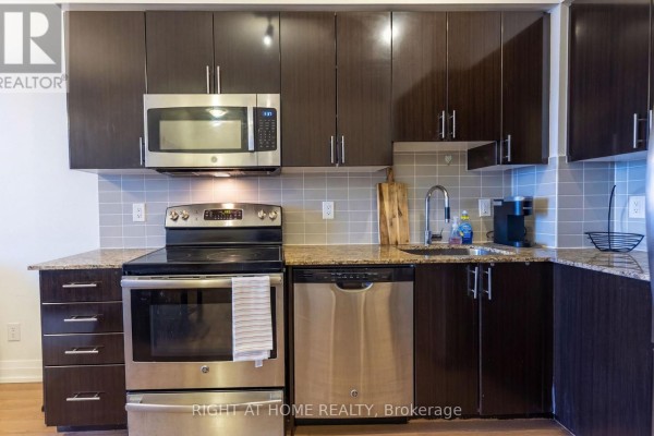 Close-up of a kitchen with dark cabinets, stainless steel appliances, and granite countertops. - 815 - 7167 Yonge Street, Markham