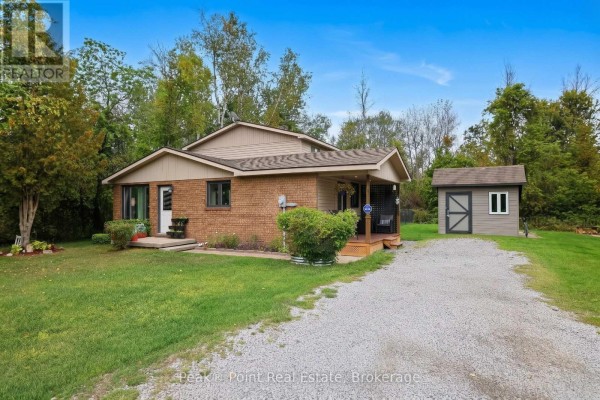 Front exterior of a brick bungalow with a covered porch and a detached shed. - 815 Main Street, South Bruce Peninsula