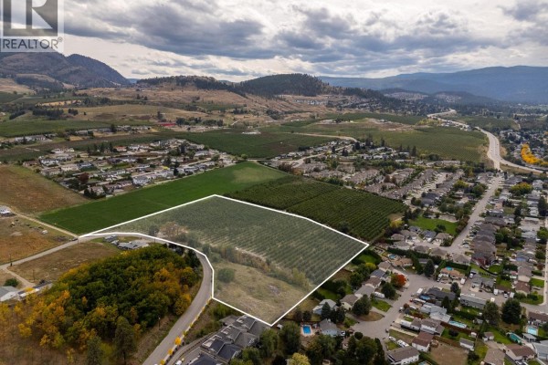 Overhead view of farm property with housing developments and hills in background. - 815 Webster Road, Kelowna