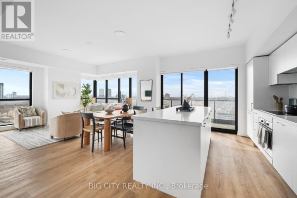Living and dining area with wood floors, white kitchen island, and dining set by large windows. - 816 - 36 Brentcliffe Road, Toronto