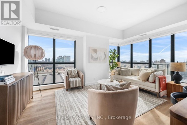 Living room with neutral-toned sofa, chairs, coffee table, large windows, and city view. - 816 - 36 Brentcliffe Road, Toronto