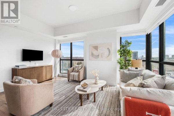Living area with sofa, accent chairs, oval coffee table, and large windows overlooking the city. - 816 - 36 Brentcliffe Road, Toronto