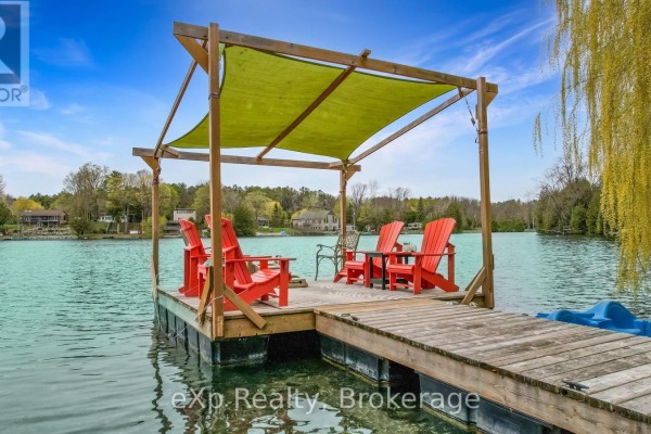 Dock with red chairs and green canopy on lake, facing yellow house. - 816 Marl Lake Road 8, Brockton
