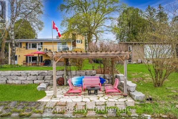 Outdoor seating area with pink chairs under a wooden pergola by the water. - 816 Marl Lake Road 8, Brockton