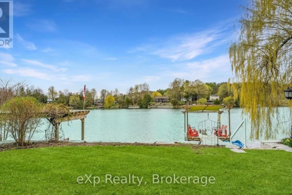 View of a lake with houses and trees across the water from the shore. - 816 Marl Lake Road 8, Brockton