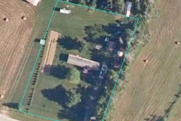 Aerial view of a property with a long house, trees, and scattered storage units and vehicles. - 816 Williamstown, Williamstown