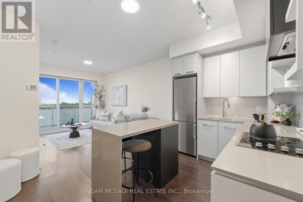 Living room and kitchen area with a sofa, coffee table, and modern kitchen island. - 817 - 1830 Bloor Street W, Toronto