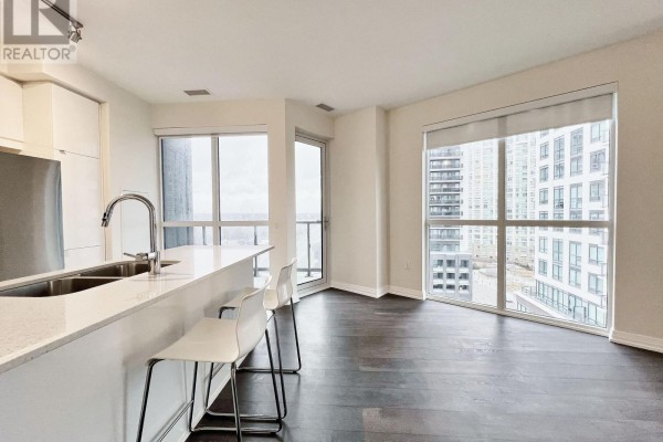 Kitchen island with white quartz countertop, stainless steel sink, and bar stools. - 817 - 50 Thomas Riley Road, Toronto