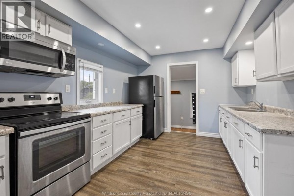 Kitchen with white cabinets, granite countertops, stainless steel appliances, and light blue walls. - 817 Chatham Street East, Windsor