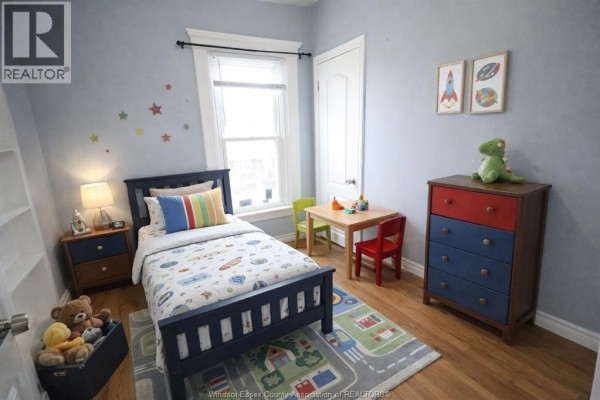 Child's bedroom with a navy blue bed, a small table and chairs, and a colorful dresser. - 817 Chatham Street East, Windsor