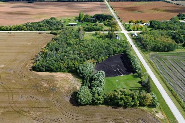 Aerial view of land parcel with trees, a cleared dark area, and surrounding fields. - 817 Cloverdale Road, St Andrews