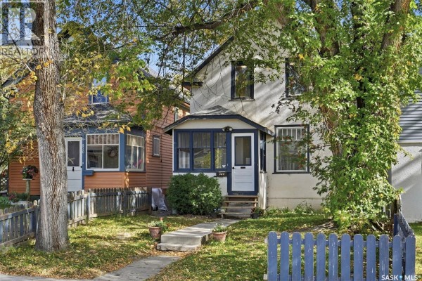 Front exterior of a two-story house with white siding and dark blue trim. - 818 B Avenue N, Saskatoon