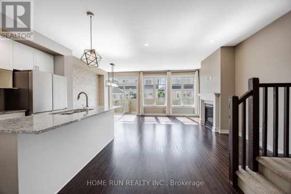 Kitchen with white cabinetry, stainless steel appliances, granite countertops, and an island with a sink. - 818 Clapham Terrace, Ottawa