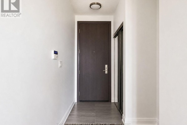 Apartment hallway with a dark wood front door and a closet door on the right. - 819 - 15 Water Walk Drive, Markham