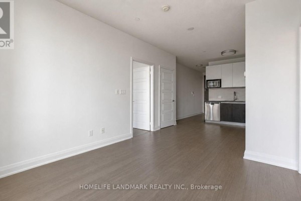 Empty apartment living area with light wood floors and access to a kitchen. - 819 - 15 Water Walk Drive, Markham