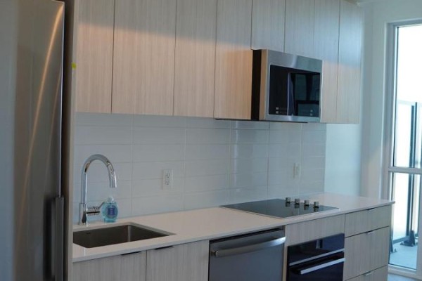 Modern kitchen with stainless steel appliances, white subway tile backsplash, and light wood cabinets. - 819 - 20 Deans Drive, Toronto