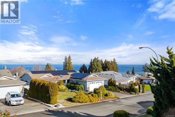 Aerial view of a suburban street with houses and a distant ocean view. - 819 Athena Pl, Nanaimo