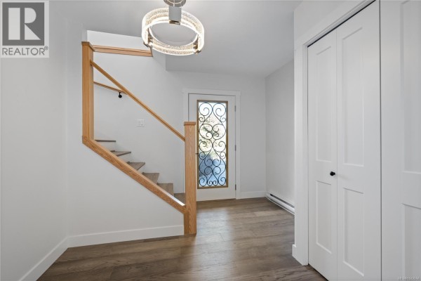 Interior entryway with a wooden staircase, dark wood floors, and a closet. - 819 Athena Pl, Nanaimo