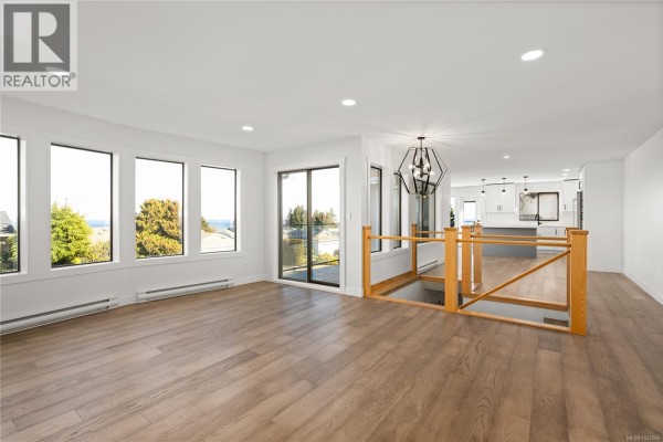Living room with large windows overlooking the ocean and an open-concept kitchen. - 819 Athena Pl, Nanaimo