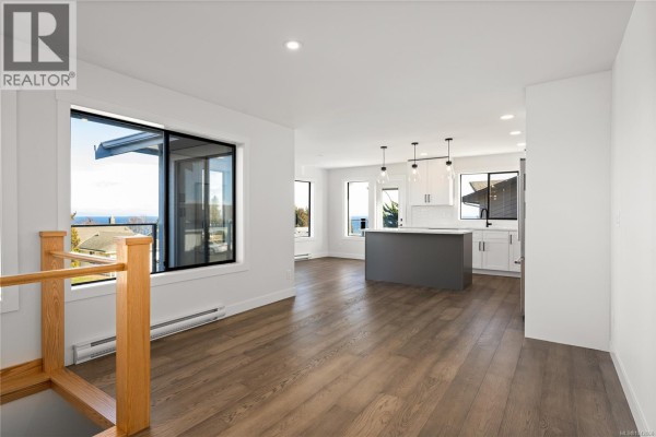 Open-concept living area with a large window, view of the ocean, and modern kitchen. - 819 Athena Pl, Nanaimo