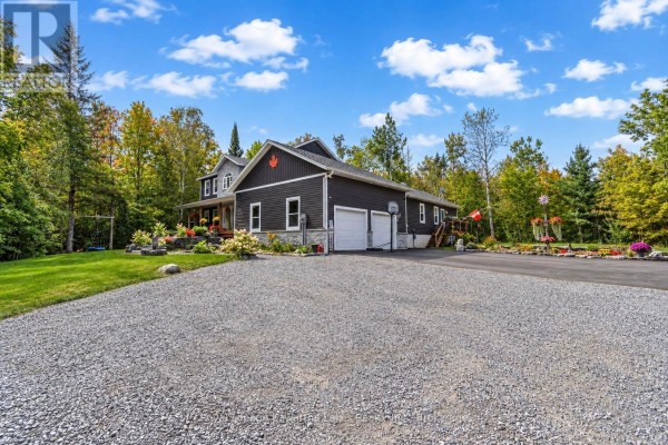 Dark-sided two-story house with attached garage and covered porch in daytime. - 819 County 49 Road, Kawartha Lakes