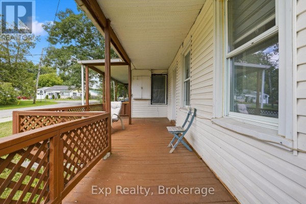 View of a wooden covered porch with chairs and white siding on the house. - 82 - 84 Bursthall Street, Marmora And Lake