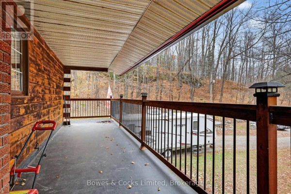 Covered porch with lawnmower and trailer view - 82 Bay Lake Road Bancroft