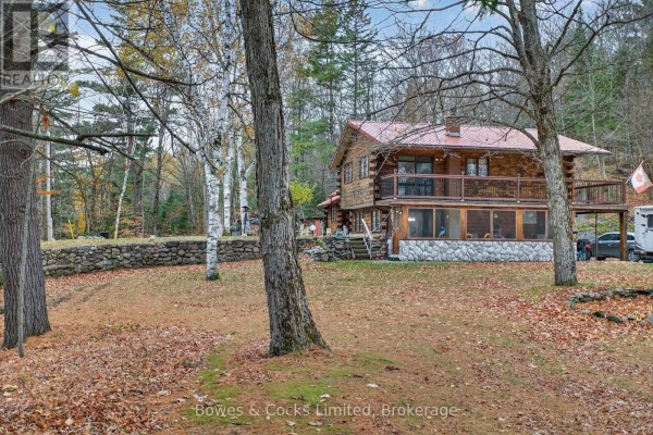 Log cabin with stone foundation, balcony, and covered porch - 82 Bay Lake Road Bancroft