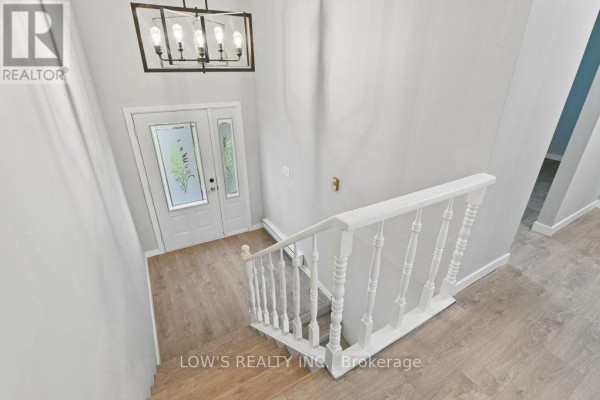 View from upstairs landing looking down at the entryway and staircase with a modern chandelier. - 82 Bertha Street, Champlain