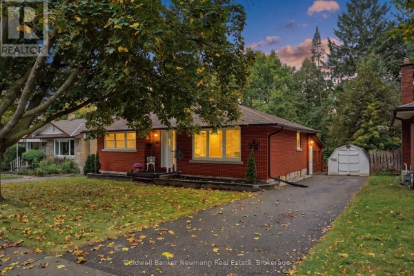 Exterior shot of the brick house and driveway at dusk. - 82 Knightswood Boulevard, Guelph