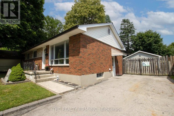 Side view of the bungalow, featuring the red brick facade, garage, and driveway. - 82 Langton Road, London East